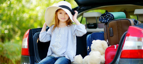 adorable little girl in summer hat leaving for a car vacation with her parents