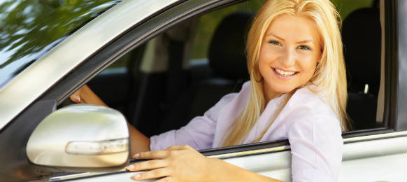 attractive blonde young woman at the wheel in her car rental