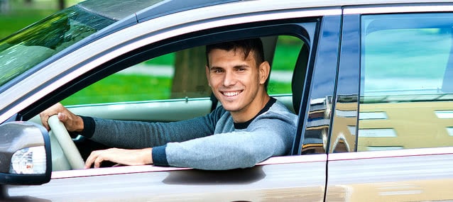 smiling guy inside his rental car ready to drive