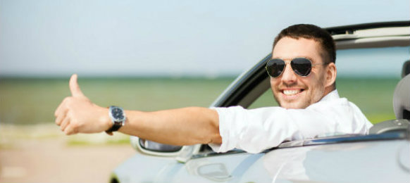 Man giving a thumbs up while riding a convertible car