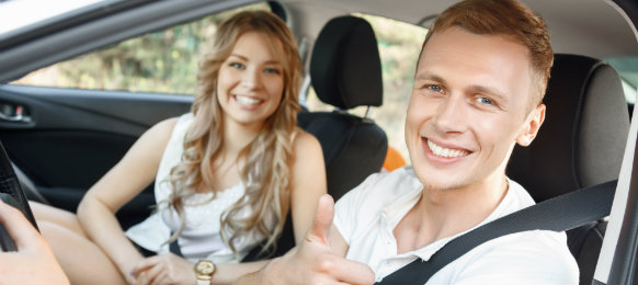 A man giving a thumbs up while beside her girlfriend in the car