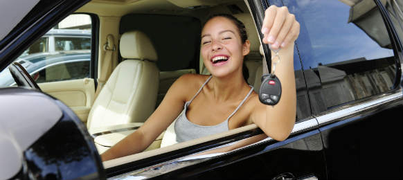 smiling woman showing keys of her expensive car rental