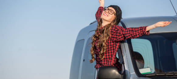 woman enjoying the breeze outside her rental car