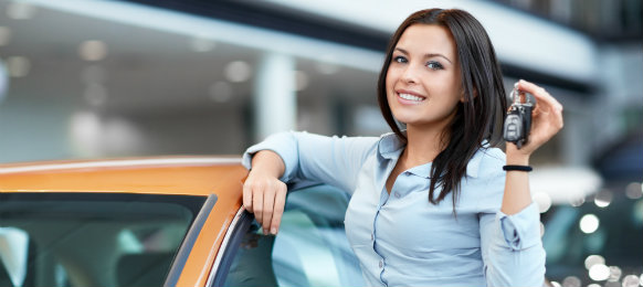 Woman beside her orange car holding a car key