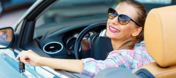 young pretty woman in sunglasses sitting in a convertible car with the keys in hand