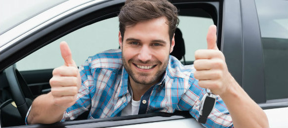 smiling guy giving a thumbs up sign inside his car